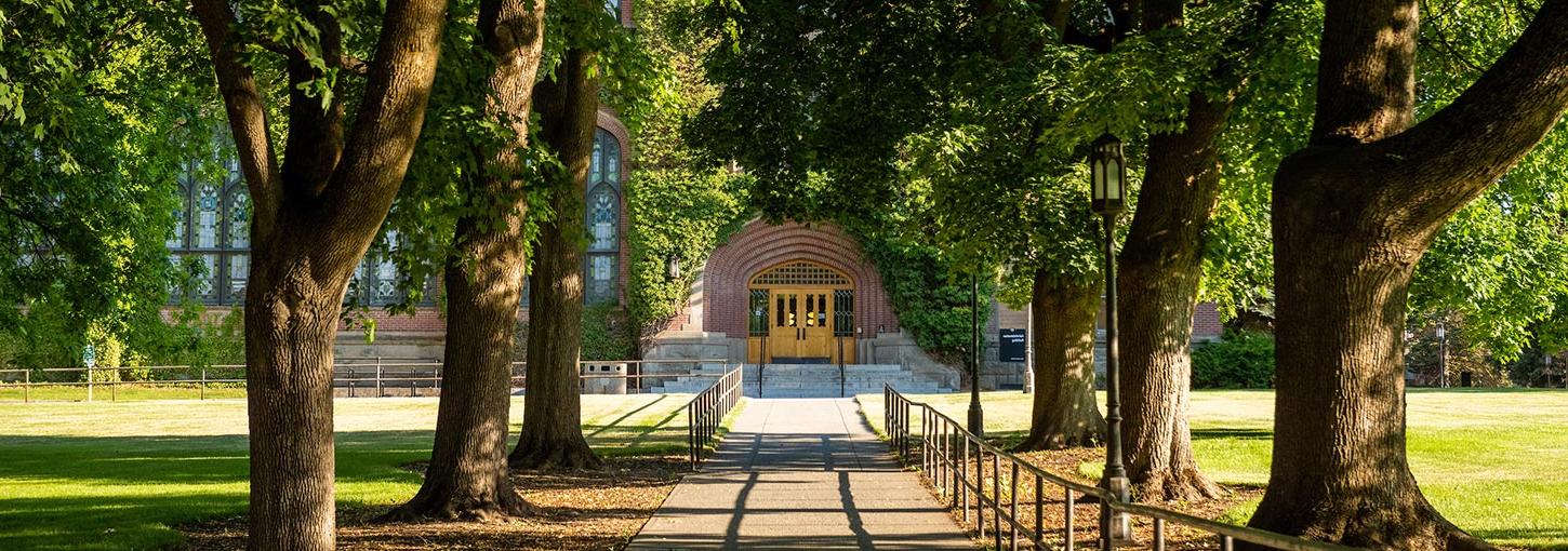 A path along Admin Lawn shaded by trees, leading to the north doors of the Administration Building.