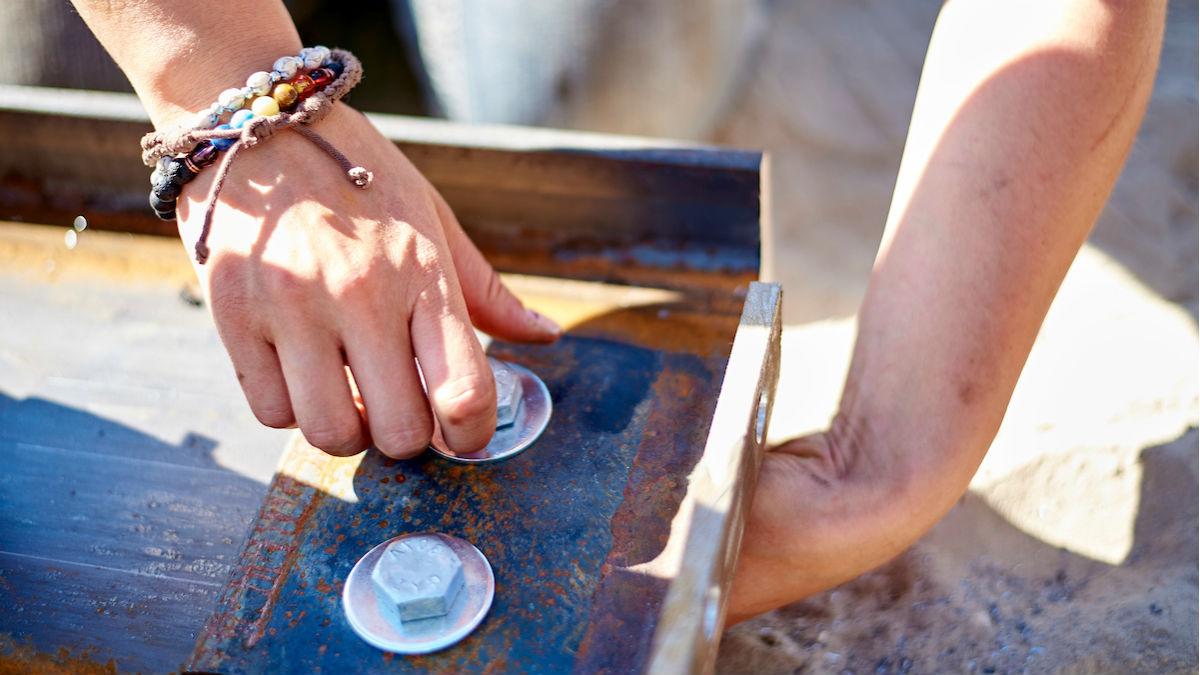 A view of a student's hands tightening a nut.