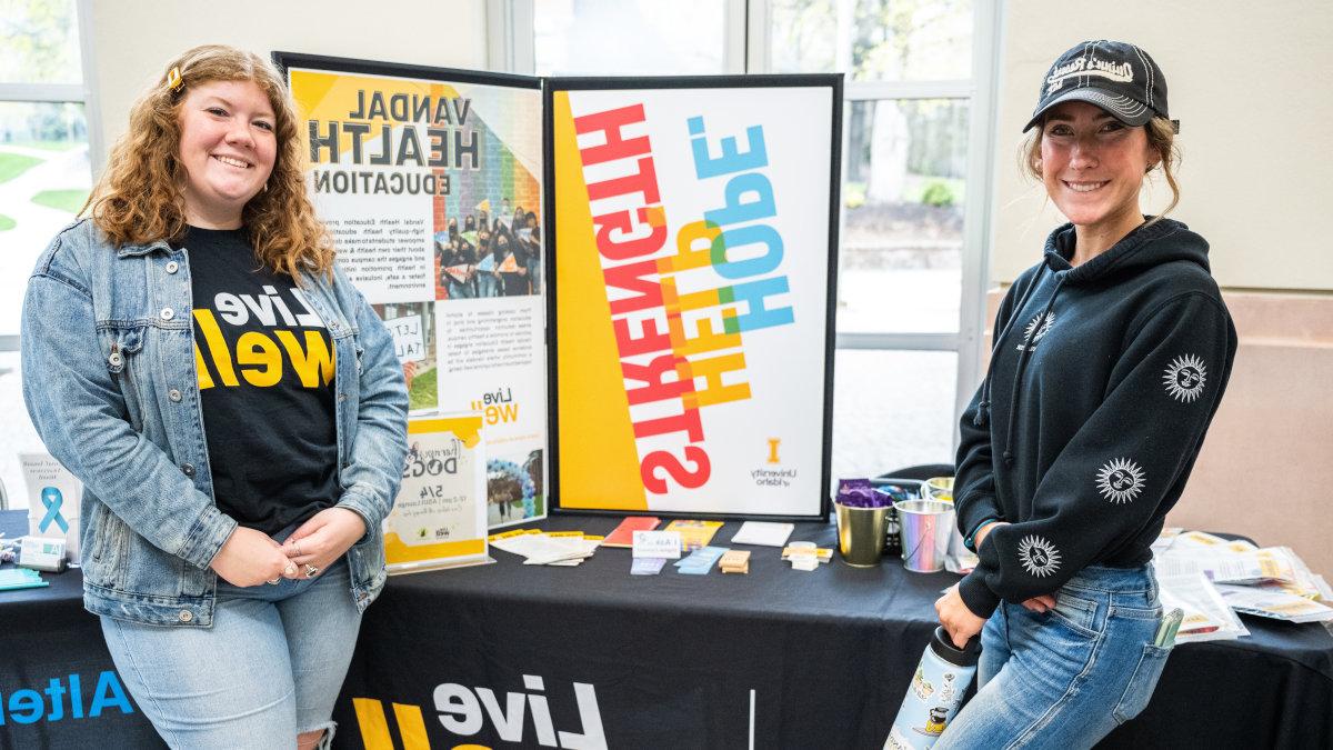 Two U of I students standing in front of a table display.