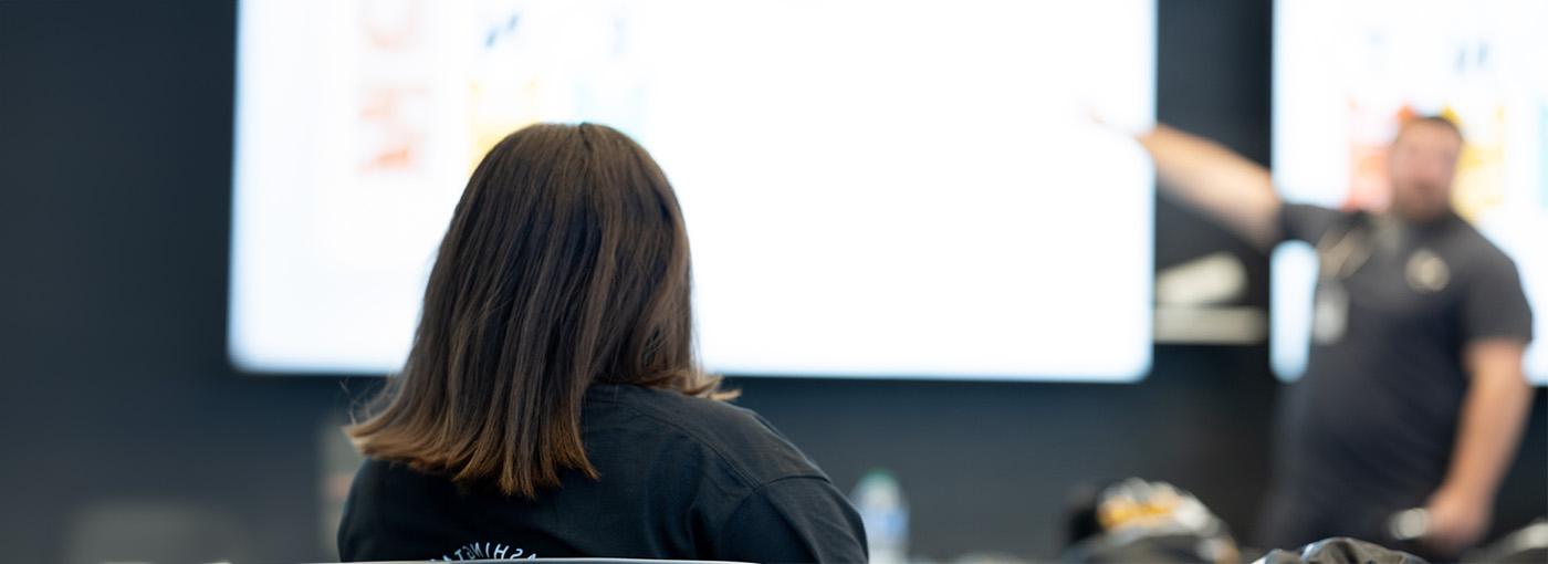 A student sits in front of a screen. 